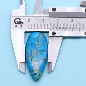 Vue macro montrant les dimensions d'un pendentif en pierre bleue en forme de gouttelette