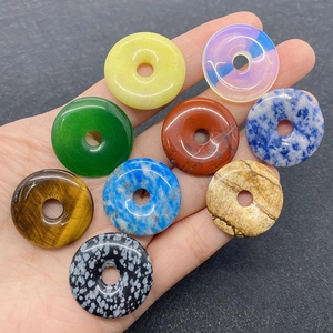Macro detail of various round semi-precious stone donuts held in hand for size reference