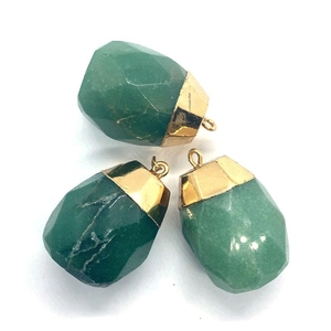 Detailed macro view of three faceted green natural stone cylinder pendants with gold caps