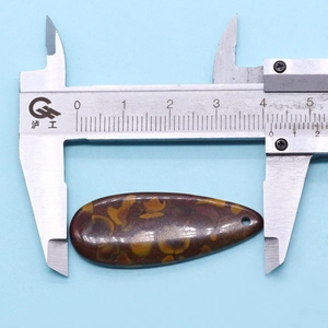 Macro shot measuring the 42mm teardrop synthetic turquoise stone pendant with a digital caliper