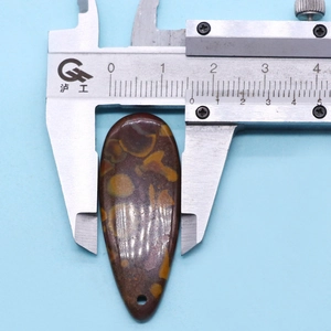 Macro shot of a teardrop-shaped natural stone pendant being measured by a digital caliper