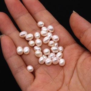 Macro detail of rice-shaped natural freshwater pearls held in palm over black background