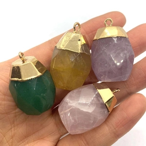 Hand holding faceted natural stone cylinder pendants with gold plated caps in four colors