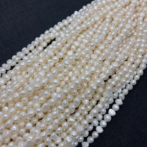 Detailed view of natural white freshwater pearls with soft luster on black texture
