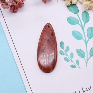 Polished teardrop natural stone pendant with dark mineral textures on a decorative background