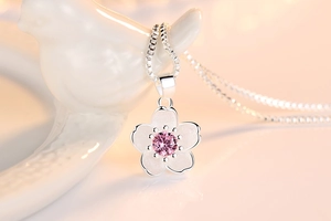 Macro detail of cherry blossom pendant with pink zircon and frosted silver texture