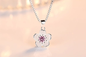 Close-up of silver flower pendant with matte petals and pink zircon centerpiece