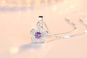 Detail of silver cherry blossom pendant featuring matte petals and purple zircon stone
