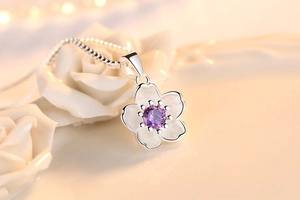 Detailed macro view of a silver cherry blossom pendant with a purple central zircon stone
