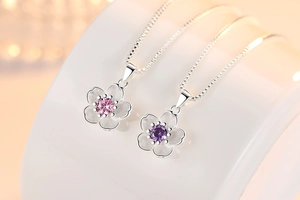 Detailed macro of pink and purple peach blossom pendants on silver box chains