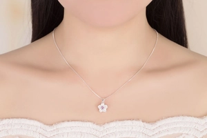 Silver cherry blossom pendant necklace with pink zircon on a model in white lace