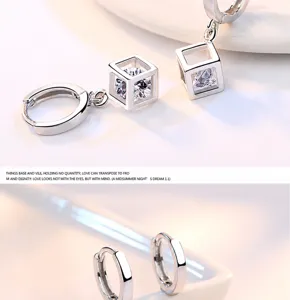 Detalle de pendientes de plata con cubo geométrico y piedra de circonita brillante