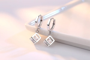 Foto macro de pendientes de cubo geométrico plateados con piedra de circón brillante