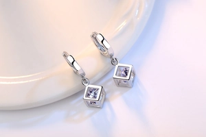 Detalle macro de pendientes de aro cúbicos geométricos de plata con circonitas