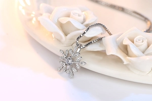 Macro shot of a snowflake pendant necklace with central diamond and pave side stones