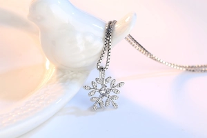 Macro shot of silver snowflake pendant with leaf textures and sparkling center stone