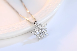 Macro detail of snowflake pendant with central crystal and leaf texture on box chain