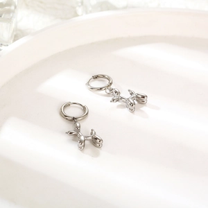 Polished silver balloon dog hoop earrings on a white minimalist ceramic tray