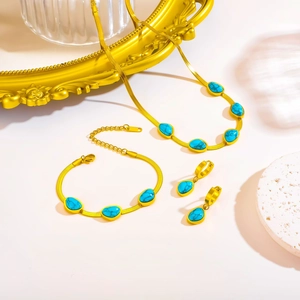 Makroaufnahme von Türkissteinen in goldener Schlangenkette und passendem Ohrring-Set