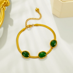 Détail du bracelet chaîne serpent doré orné de trois pierres ovales d'un vert émeraude intense