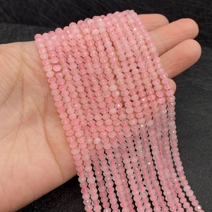 Détail de perles de quartz rose facettées montrant la texture fine tenue à la main