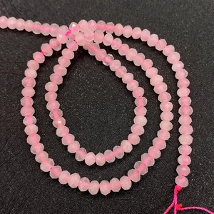 Vue détaillée de perles de quartz rose facettées à texture translucide sur fond noir