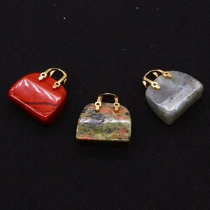 Macro view of handbag-shaped gemstone pendants in red jasper, unakite, and labradorite stones