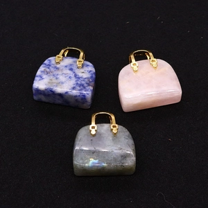 Macro shot of three natural stone handbag pendants with gold metal handles on black background