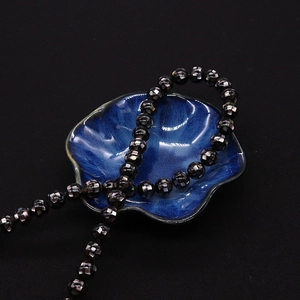 Gros plan de perles rondes en mosaïque de nacre noire de 8-20mm dans un plat en céramique