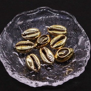 Macro detail of electroplated gold conch shell beads on a textured glass plate