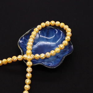 Vue détaillée des perles mosaïques en nacre jaune avec motif en damier blanc sur céramique