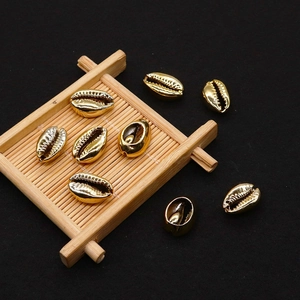 Close-up of golden metallic sea shell beads with serrated textures on a bamboo tray