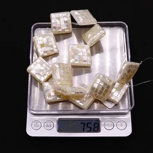 Macro detail of 20mm square mosaic shell beads on a scale weighing 75.8 grams