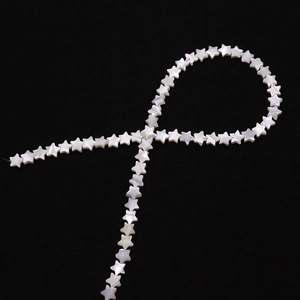 Macro shot of white star-shaped mother of pearl beads with natural luster on black background