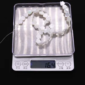 Detail van witte schelp bloemkralen op een weegschaal van 16,4 gram voor DIY sieraden