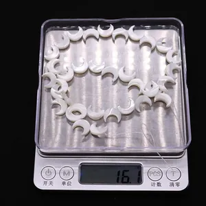 Cuentas de nácar blanco en forma de luna en una báscula con un peso de 16,1 g
