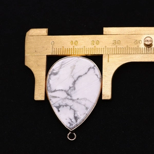 Vue détaillée d'un pendentif en pierre goutte avec bordure dorée et pied à coulisse