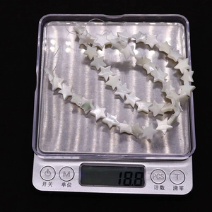 Macro shot of 18.8g natural star-shaped shell beads on a digital scale for weight check
