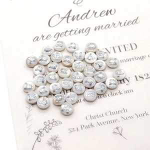 Macro detail of white shell beads featuring delicate silver butterfly designs for DIY jewelry