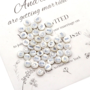 Macro detail of white shell beads with silver owl motifs for DIY necklace jewelry making