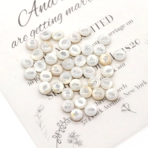 Macro shot of 6mm white shell beads featuring silver Hamsa Hand prints for jewelry DIY