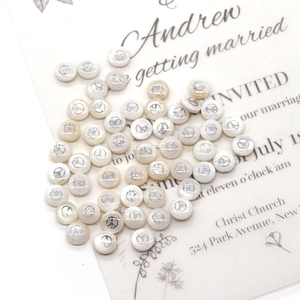Macro shot of 6mm white shell beads with silver lightning moon icons for DIY jewelry