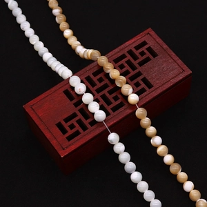 Natural white and brown seashell round beads on a traditional red wooden jewelry box