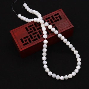 Close-up of polished white natural sea shell round beads on a traditional wooden gift box