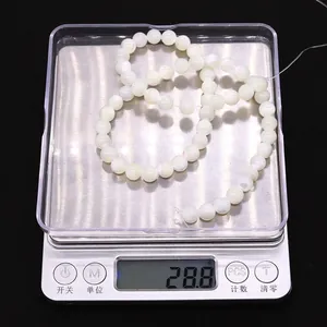Detailopname van natuurlijke witte schelpkralen op een digitale weegschaal van 28,8g