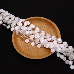 Natural white freshwater shell beads in fan shape on a wooden tray for DIY jewelry making
