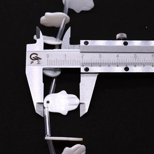Close-up measurement of hand-shaped natural shell bead with digital caliper