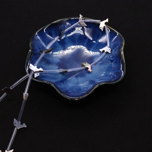 Macro detail of colorful dolphin-shaped shell beads and glass tubes in a blue bowl