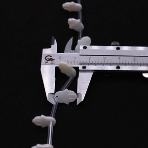 Macro view of white Hamsa shell beads showing 10.5mm width measurement on a caliper