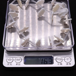 Detailed view of white Hamsa Hand shell beads on a scale weighing 16.3g